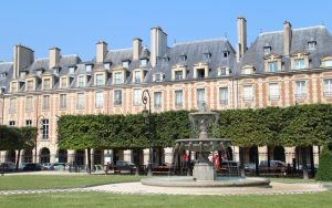 Place des Vosges (ancienne Place Royale) vue du square Louis XIII et de la fontaine au centre.